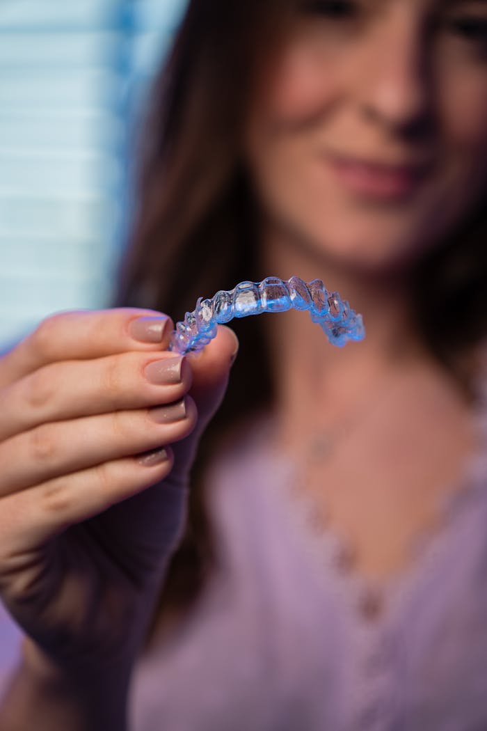A woman showing an invisible orthodontic aligner in a dental clinic.