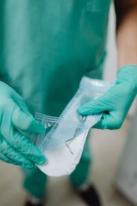 Close-up of a dentist opening a sterile pack with dental instruments wearing gloves.